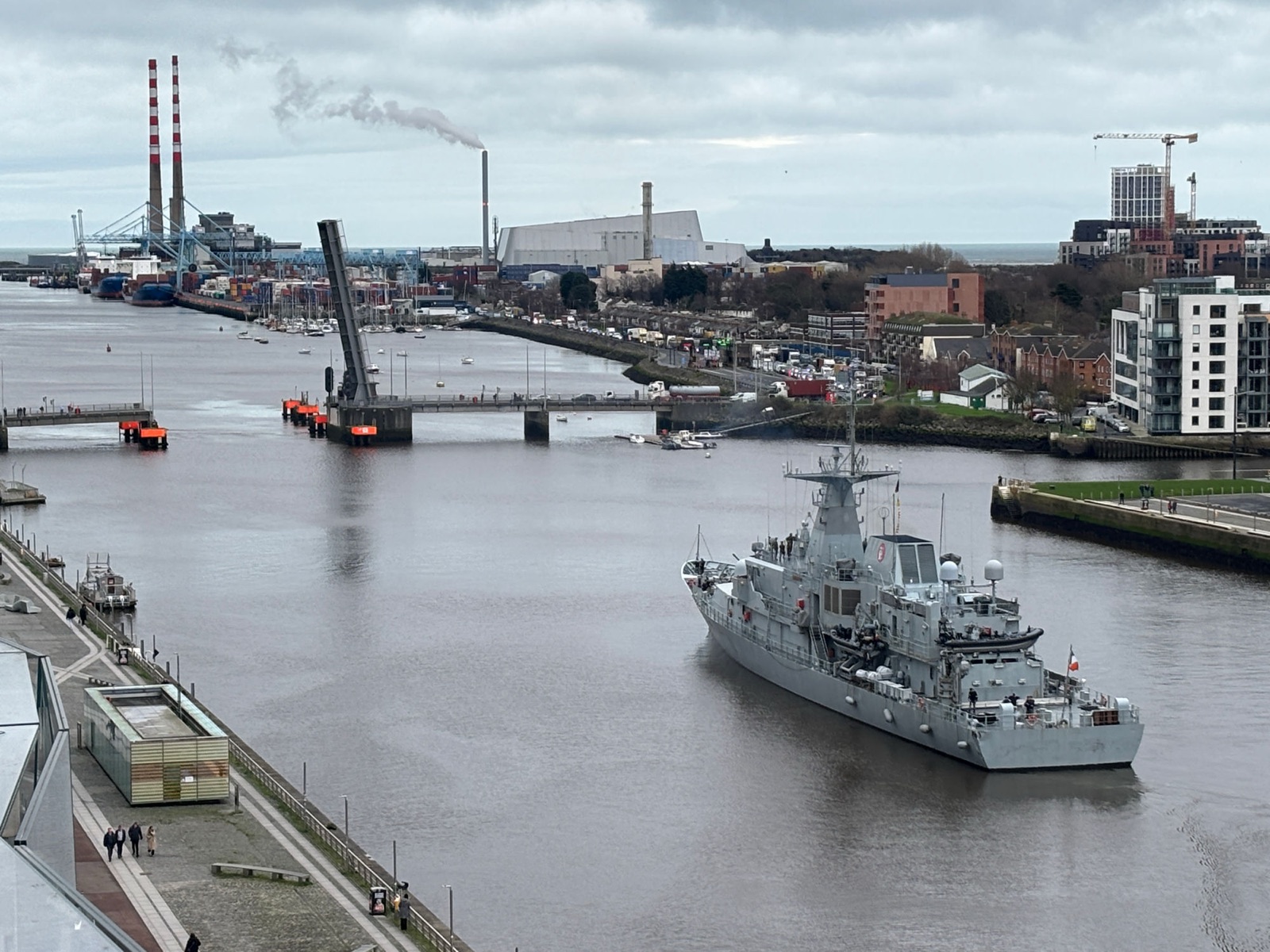 An Irish Naval Service vessel on the River Liffey at Dublin Port, with the Poolbeg chimneys and the East-Link bridge behind